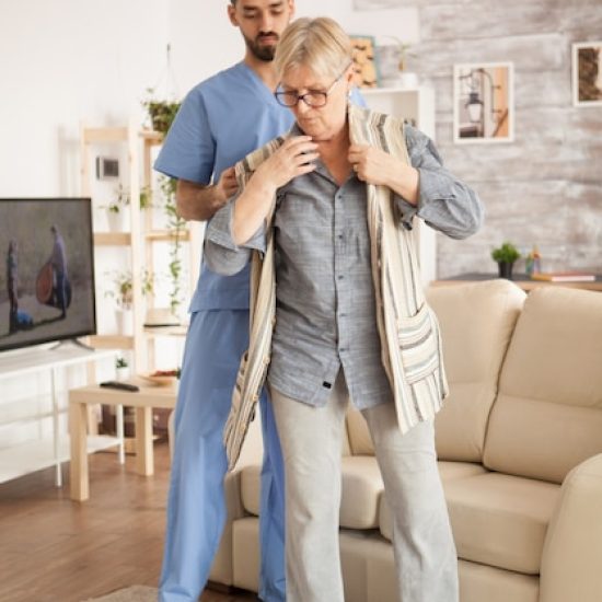 male-doctor-nursing-home-wearing-blue-uniform-helping-senior-woman-dress_482257-22545