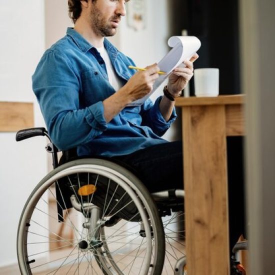 young-businessman-wheelchair-going-through-paperwork-while-working-home_637285-5774